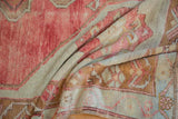 Textured pile of a distressed Oushak runner in muted cherry red, bronze, and oxidized tones.