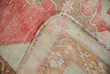 Distressed Oushak runner's cherry red pile and light woven back with faded geometric patterns.