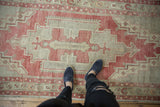 Faded red and beige distressed Oushak runner with stepped geometric pattern underfoot.