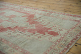 Distressed vintage Oushak runner with faded cochineal red floral vinery and even pile wear.