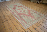 Vintage Oushak rug corner with distressed red and beige geometric border and intact selvage.