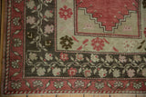 Distressed Oushak rug corner, faded raspberry and charcoal meandering vine borders, stepped spandrel.
