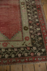 Charcoal brown main border with delicate vine and rose motif on distressed Oushak rug.