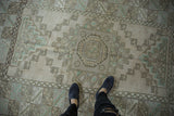 Distressed vintage Melas rug's geometric lattice in ivory, seafoam, and charcoal tones.