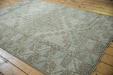 Distressed vintage Melas rug with low pile, geometric lattice, and serrated border motifs.