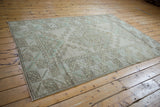 Geometric seafoam and beige pattern with worn pile on distressed vintage Melas rug.