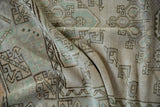 Textured, distressed pile of a vintage Melas rug, showing geometric motifs in seafoam green and muted beige.