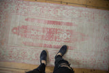 Abrashed pale raspberry red field and ivory ram's horn border of the Oushak runner.