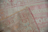 Vintage distressed Oushak rug corner revealing its soft pink pile and intact selvage.