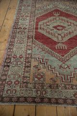 Distressed vintage Oushak rug, cherry red medallion, grey field, and serrated motifs.