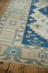 Distressed Oushak carpet texture: indigo blue Samovar border, ivory field, pale blue serrated leaves.