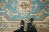 Distressed vintage Oushak rug section with denim blue field and geometric pearl motifs.