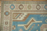 Worn denim blue, ivory, and pale rose geometric patterns on vintage distressed Oushak corner.