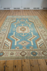 Vintage Distressed Oushak rug corner showing geometric denim blue and beige patterns.