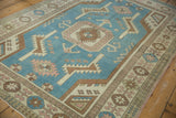 Distressed Oushak rug border detail featuring geometric patterns in pale rose and blue.