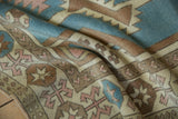 Distressed texture of vintage Oushak rug with geometric arrowhead motifs in blue, brown, and rose.