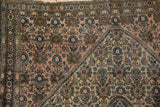 Intricate henna plant motif and medallion corner on antique Farahan Sarouk rug, with visible wear.