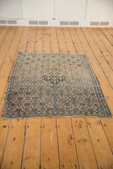 Antique Farahan Sarouk rug corner with worn ivory pile and tattered fringe.