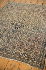 Tattered fringe and border with dusty rose, blue, and ivory patterns on an antique Persian Farahan rug.