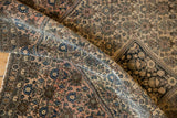 Folded antique Farahan Sarouk rug highlighting fine weave, blossomed henna plant motif, and time-softened hues.