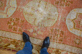 Vintage Khotan runner, pale orange, ivory, gold patterns, worn texture under black boots.