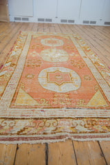 Vintage Khotan runner with pale terracotta and ivory triple medallion, showing pile wear.