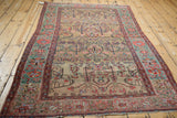 Angled view of the antique Farahan Sarouk rug, showing the full length of its gold field and green border.