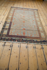 Vintage distressed Khotan rug corner, showing navy border, pale terracotta vinery on slate blue.