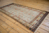 Distressed Khotan rug corner, revealing navy geometric and madder red borders with delicate motifs.
