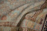 Distressed vintage Khotan rug pile, showing slate blue, terracotta, saffron hues, and foundation.