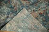 Worn vintage Mahal rug pile in dusty blue and red, folded to reveal its woven foundation.