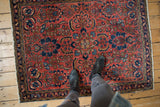 Traditional Persian Lilihan rug, brick red field with intricate navy floral vinery.