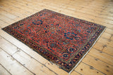 Vintage Lilihan rug corner showing brick red field with dense navy blue and gold floral vinery.