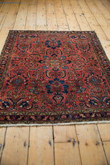 Right edge of a vintage Persian Lilihan rug with navy blue vinery, brick red field, and a gold geometric border.