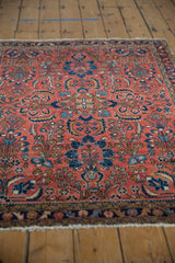 Vintage Lilihan rug corner: brick red field, dense floral vinery, navy border, and short fringe.