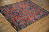 Vintage Lilihan rug corner showing brick red floral field, navy border, and tattered fringe.
