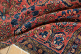 Navy blue patterned border and brick red field with floral vinery on a Lilihan rug.