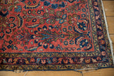 Tattered lower right corner of vintage Lilihan rug, showing brick red field and navy floral borders.