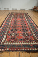 Reciprocating pawn motif borders with madder red medallions on an antique Caucasian runner.