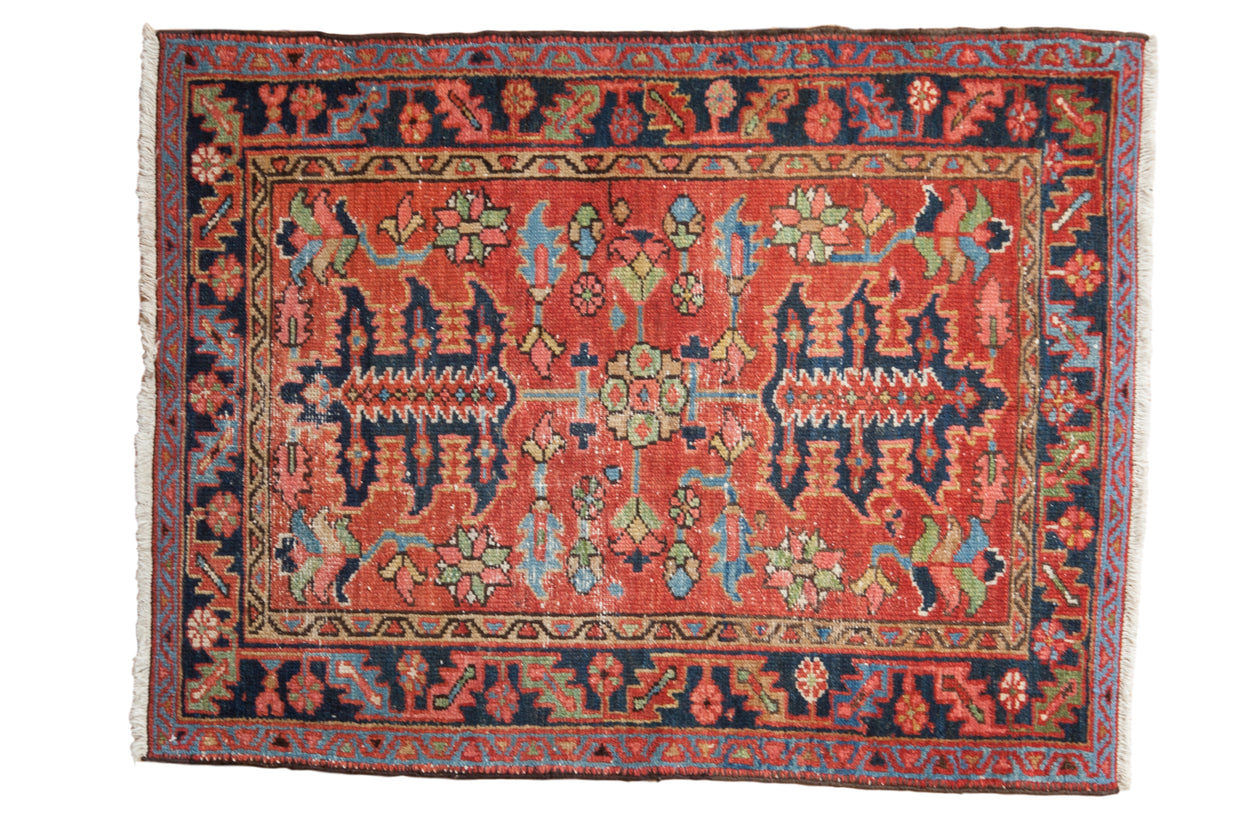 Antique Persian Heriz rug, brick red field with oversized palmettes and geometric motifs, navy border.