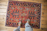 Heriz rug featuring oversized palmette finials and varied floral patterns on brick red.