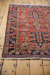 Antique Heriz rug's detailed border shows navy, brick red, and sky blue geometric floral motifs.