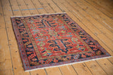 Corner of antique Heriz rug showing navy floral border, geometric motifs, brick red field.