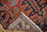 Hand-knotted Antique Heriz rug corner, showing brick red pile and tightly woven multi-color foundation.