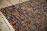 Afshar rug's repeating boteh motifs in indigo lattice, worn pile, visible foundation, selvage.