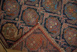 Antique Afshar rug corner reveals indigo, brick red boteh design, secure selvage, and age-consistent wear.