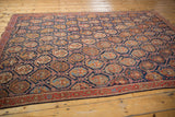 Detail of the Persian Afshar rug's indigo lattice, repeating boteh motifs, and brick red border.