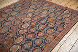 Antique Afshar rug's indigo field featuring saffron boteh motifs and brick red lattice.
