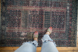 Distressed Vintage Turkmen rug with textured aubergine and charcoal field, highlighting worn plant motif.