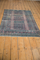 Distressed Turkmen rug, muted aubergine and charcoal geometric patterns, with visible wear.